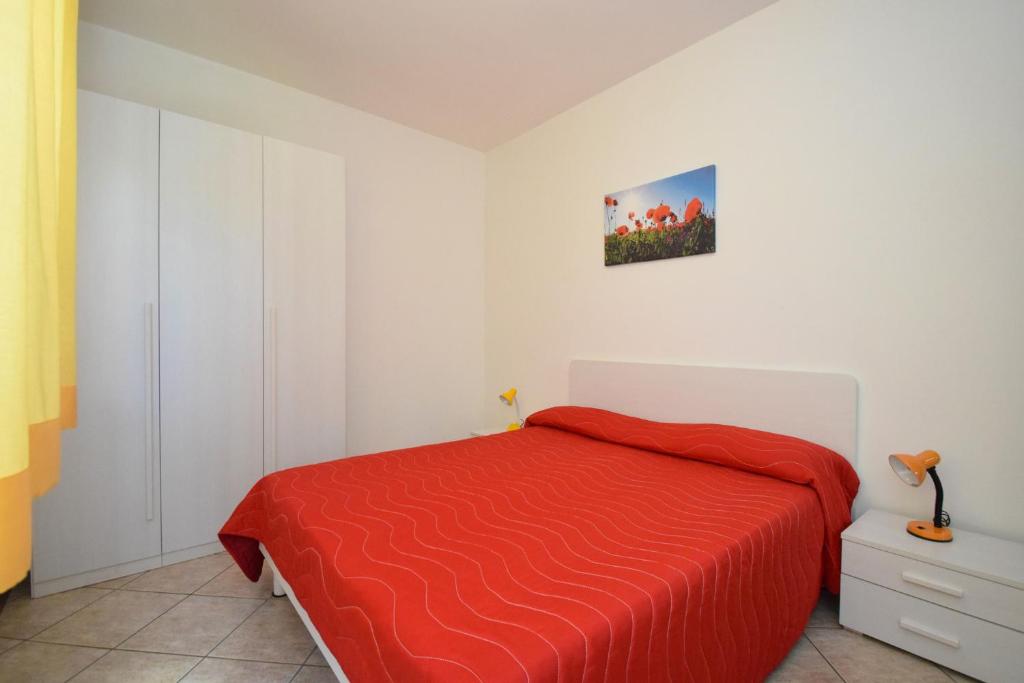 une chambre avec un lit avec une couverture rouge dans l'établissement Residence Le Magnolie, à Martinsicuro
