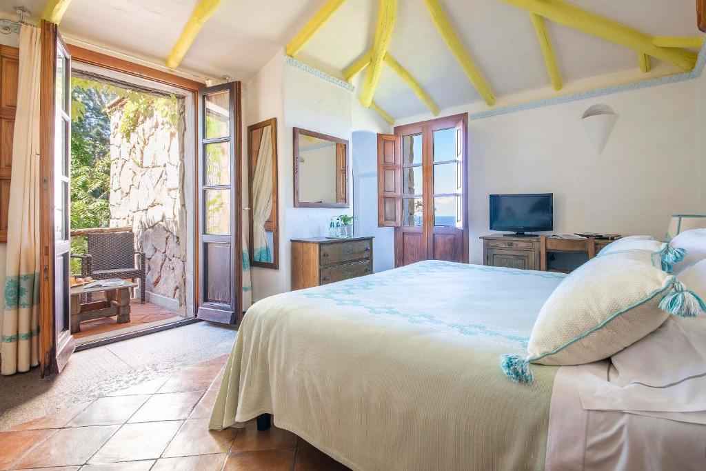 une chambre avec un grand lit et une télévision dans l'établissement Hotel Monte Turri - Adults Only, à Àrbatax