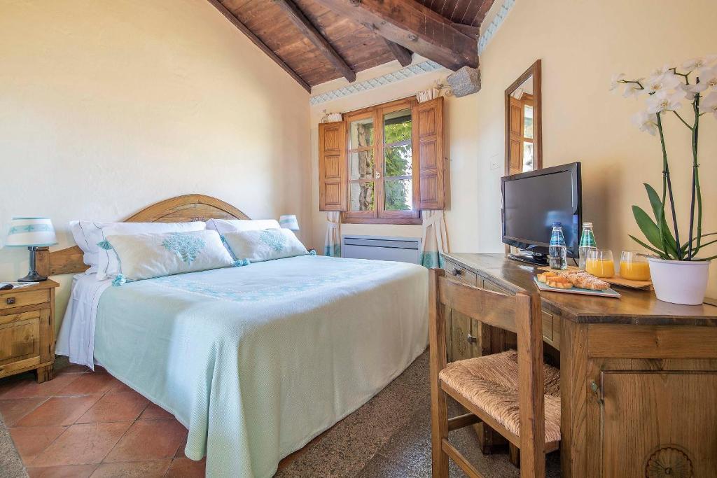 une chambre avec un lit et un bureau avec une télévision dans l'établissement Hotel Monte Turri - Adults Only, à Àrbatax