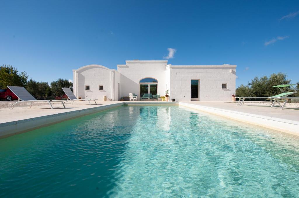 une piscine devant une maison blanche dans l'établissement TRULLI ACQUASALA - Apulian Country Experience, à Ostuni
