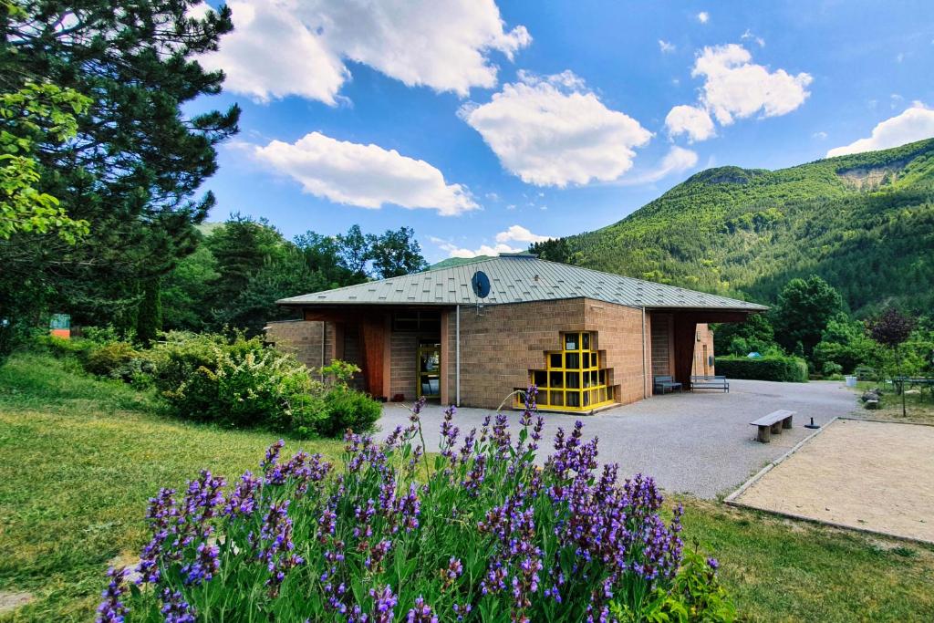 - un petit bâtiment en pierre avec un jardin et des fleurs violettes dans l'établissement Chanteduc, à Beaurières