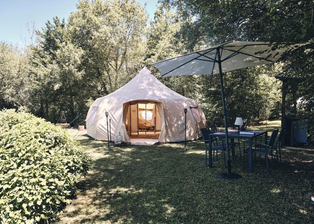 une tente blanche avec une table et un parasol dans l'établissement Camping d'artagnan, à Margouët-Meymès