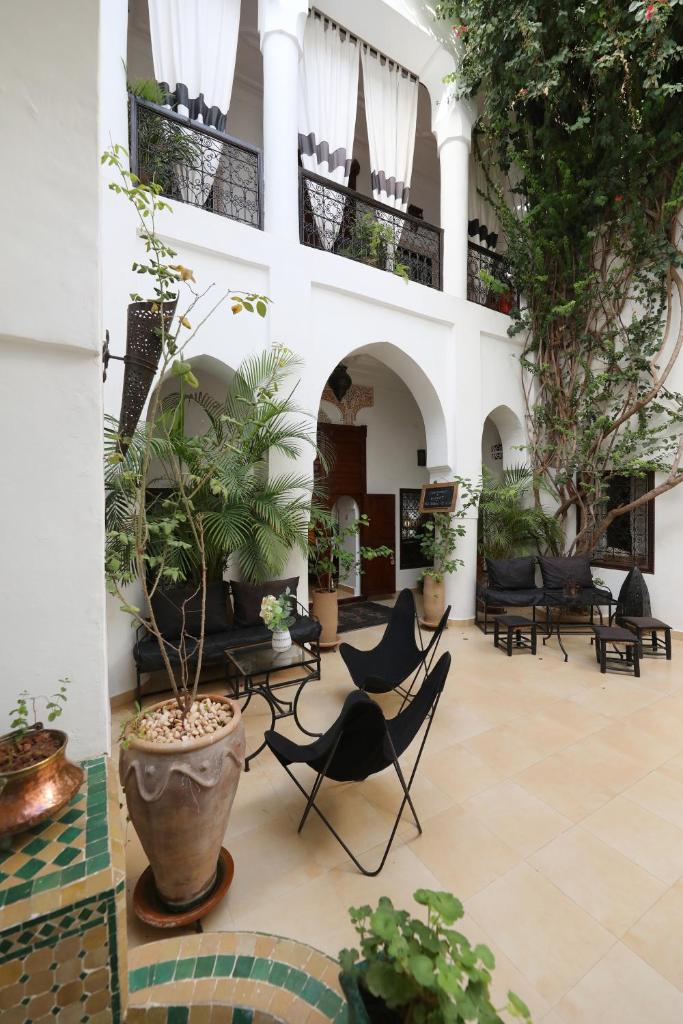 une cour avec des chaises et des plantes dans un bâtiment dans l'établissement Riad Noor Charana, à Marrakech