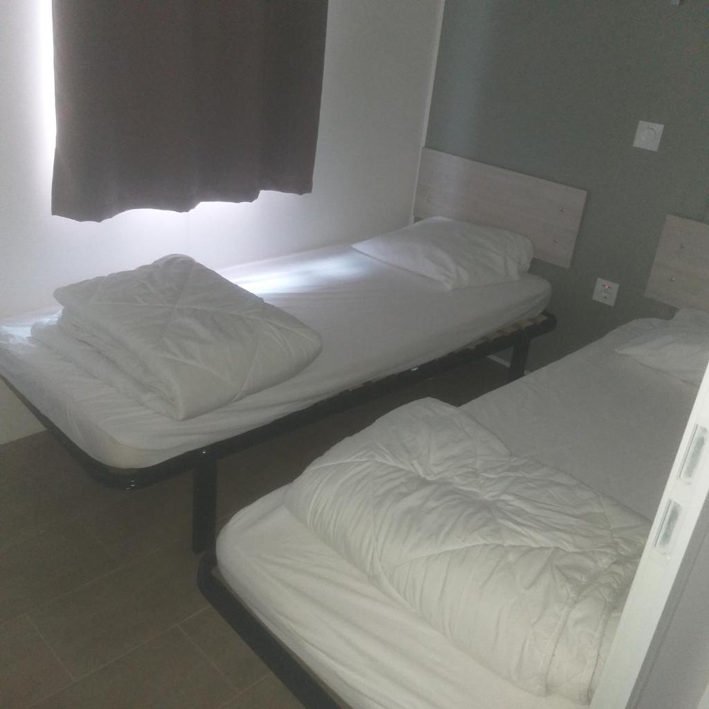 deux lits dans une chambre avec des draps blancs dans l'établissement Domaine, à Litteau