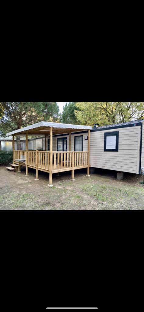 une petite maison avec une véranda et une cabine dans l'établissement MOBIL-HOME 3CH 34 m2 à SAINT-CYPRIEN, à Saint-Cyprien