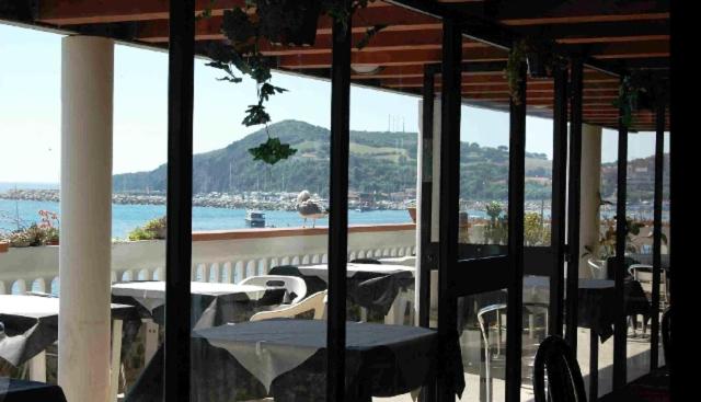 un balcon avec tables et chaises et vue sur l'eau dans l'établissement Hotel Esperia, à Piombino