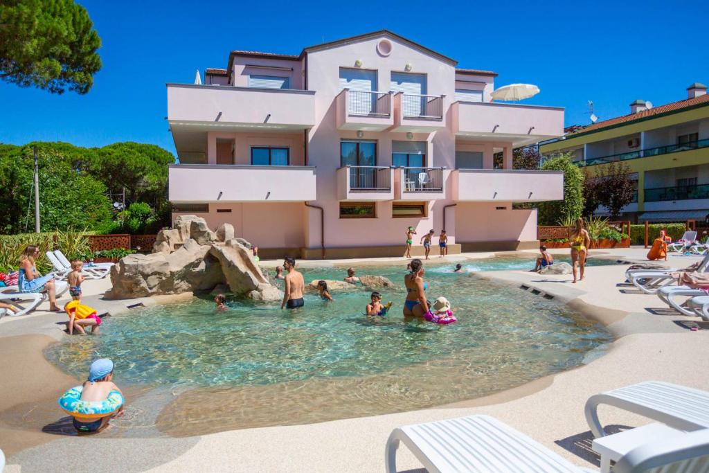un groupe de personnes dans une piscine en face d'un bâtiment dans l'établissement Bosco Canoro Bibione Resort, à Bibione