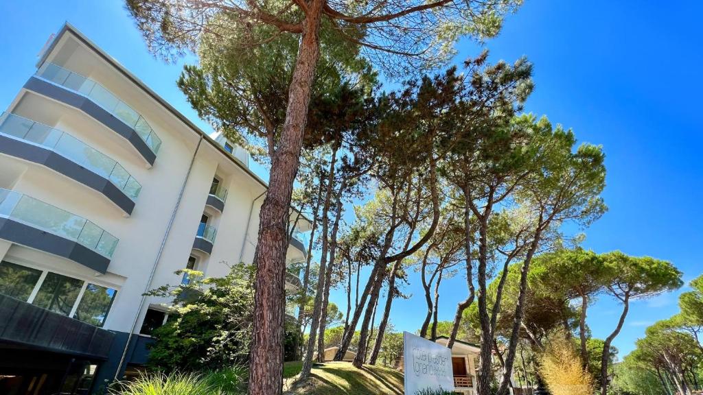 un bâtiment avec des arbres devant dans l'établissement Hotel President, à Lignano Sabbiadoro