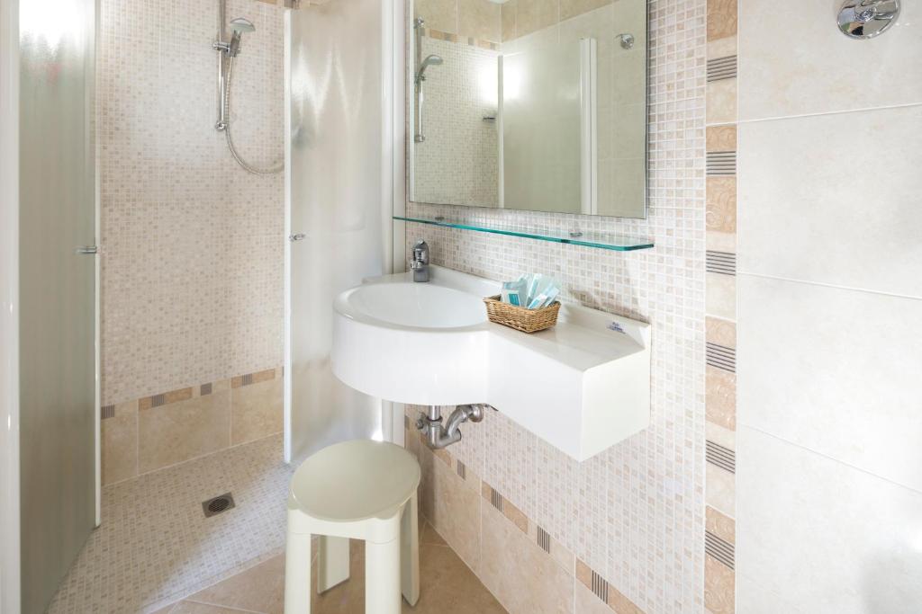 une salle de bain avec un lavabo, un miroir et un tabouret dans l'établissement Hotel Sampaoli, à Bellaria-Igea Marina