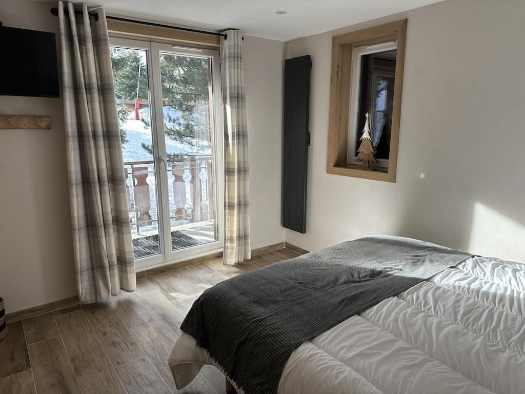 une chambre avec un lit et une grande fenêtre dans l'établissement LE REFUGE LES 2 ALPES 1800, à Les Deux Alpes