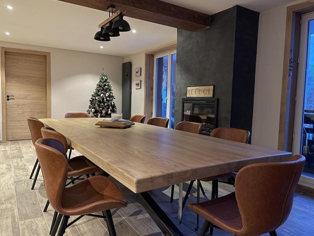 une salle à manger avec une grande table en bois et un arbre de Noël dans l'établissement LE REFUGE LES 2 ALPES 1800, à Les Deux Alpes