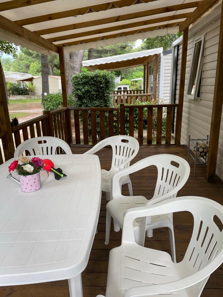 une table et des chaises blanches sur une terrasse dans l'établissement Mobil Home Camping ARGELÈS SUR MER, à Argelès-sur-Mer