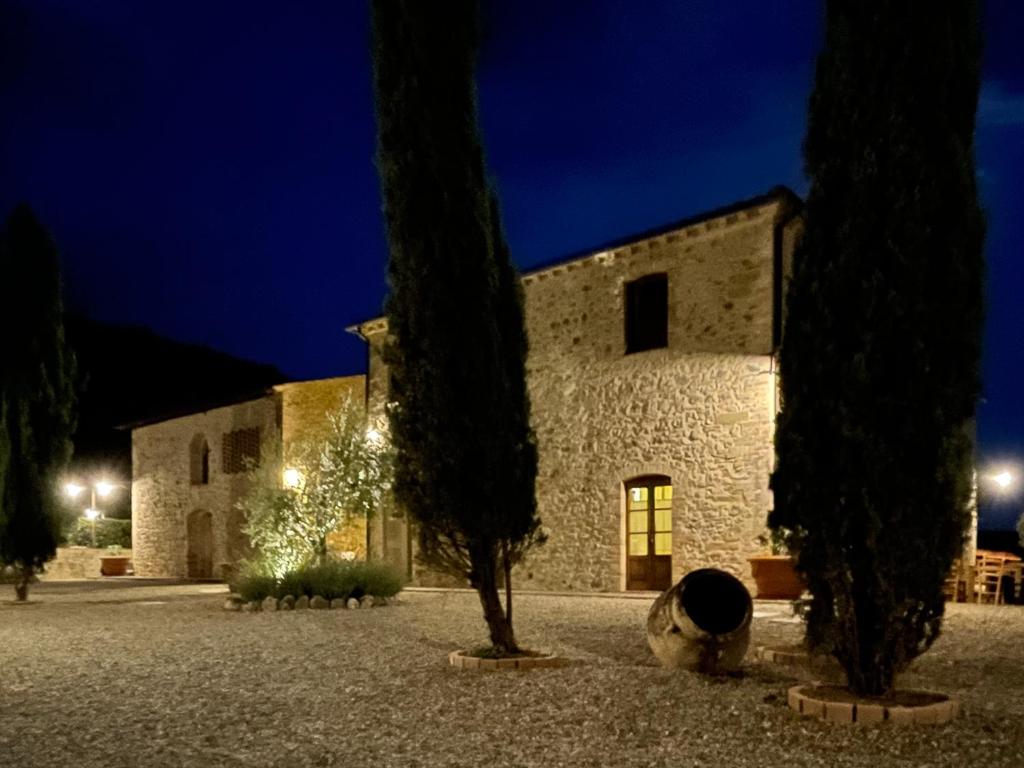 un bâtiment avec un arbre devant lui la nuit dans l'établissement Exclusive Villa with pool Borgo Pian di Sala, à San Gimignano