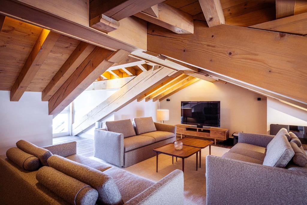 un salon avec des canapés et une télévision à écran plat dans l'établissement Les Suites de la Potinière, à Courchevel