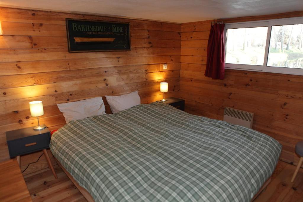 une chambre avec un lit dans une pièce aux murs en bois dans l'établissement Péniche Kairos - Havre de paix sur Canal du midi, à Toulouse
