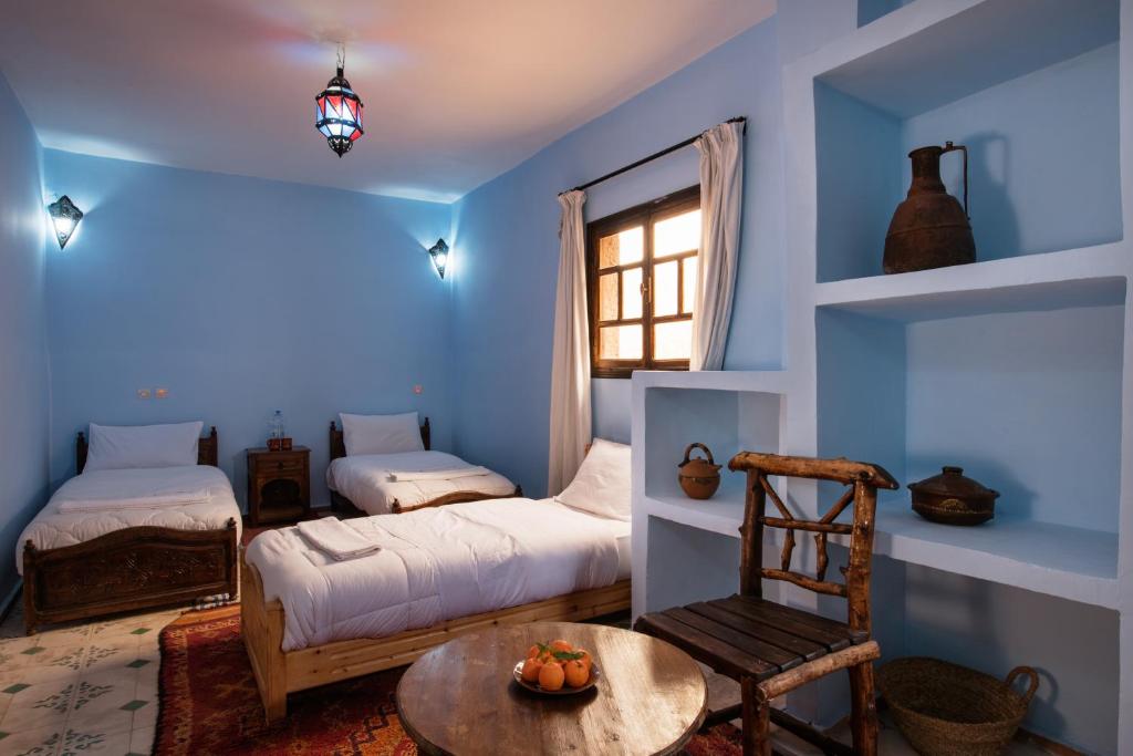 Cette chambre bleue comprend 2 lits et une table. dans l'établissement Imlil Lodge, à Imlil