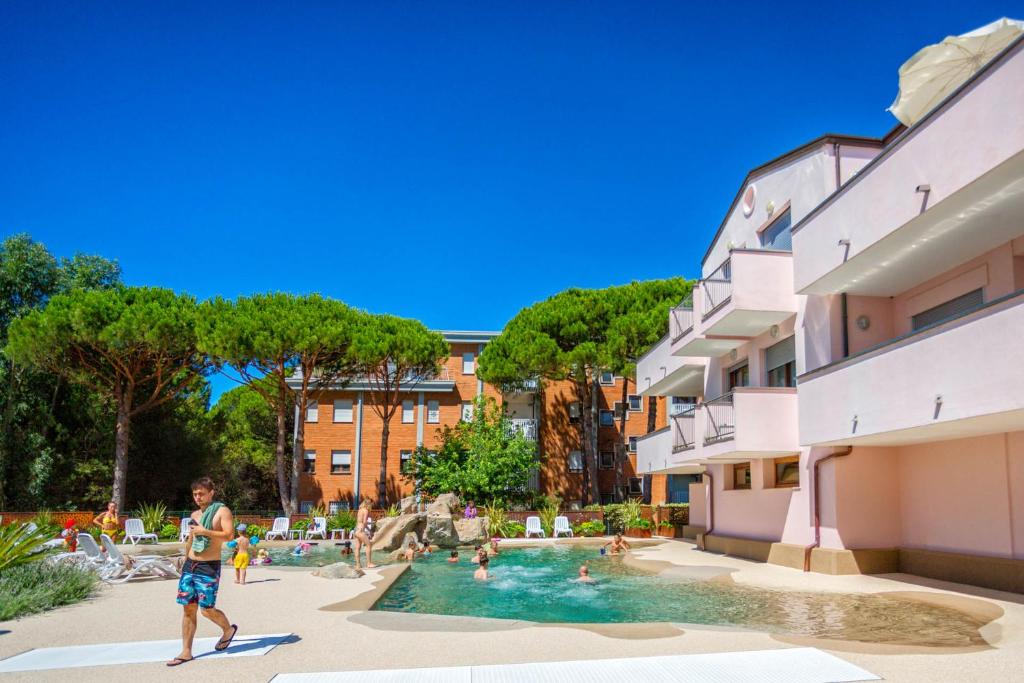 un homme debout dans une piscine à côté d'un bâtiment dans l'établissement Bosco Canoro Bibione Resort, à Bibione