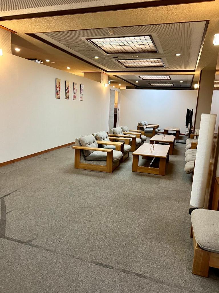 une salle d'attente avec des canapés et des tables dans un bâtiment dans l'établissement Ryokan Kousen Kazeya Group, à Nara