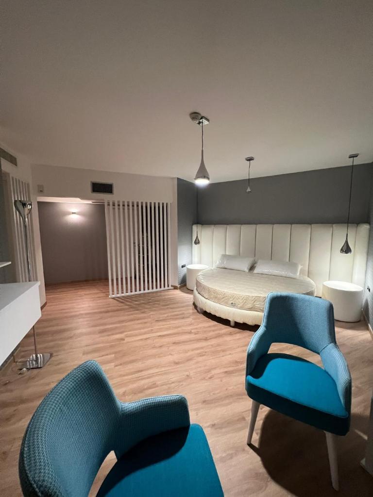 une chambre avec un lit et deux chaises bleues dans l'établissement Park Hotel Mirabeau, à Montepaone