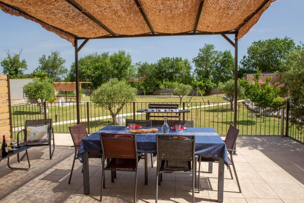 un patio avec une table et des chaises sous un toit dans l'établissement Gîtes Chantelauze, à Narbonne 37 autres photos