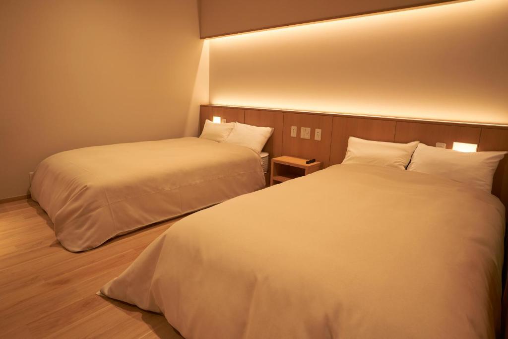 deux lits dans une chambre d'hôtel avec des draps blancs dans l'établissement Sansuiso Tsuchiyu Spa, à Fukushima 37 autres photos