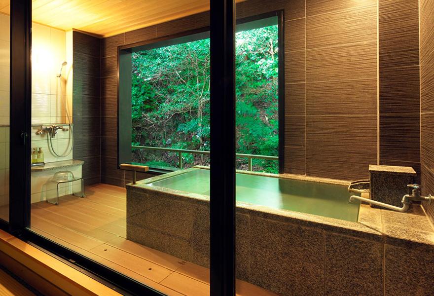 La grande salle de bains est pourvue d'une baignoire et d'une fenêtre. dans l'établissement Kagiya, à Minamiizu