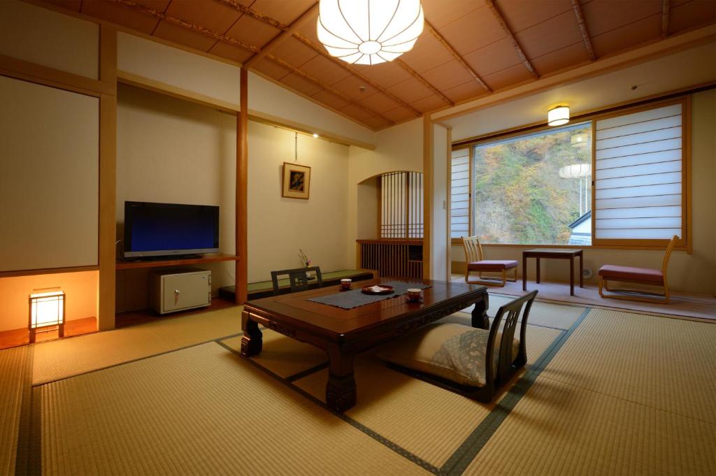 un salon avec une table et une télévision dans l'établissement Sansuiso Tsuchiyu Spa, à Fukushima