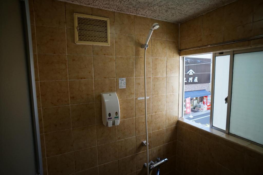 La salle de bains est pourvue d'une cabine de douche et d'une fenêtre. dans l'établissement Ryokan Katsutaro, à Tokyo 11 autres photos