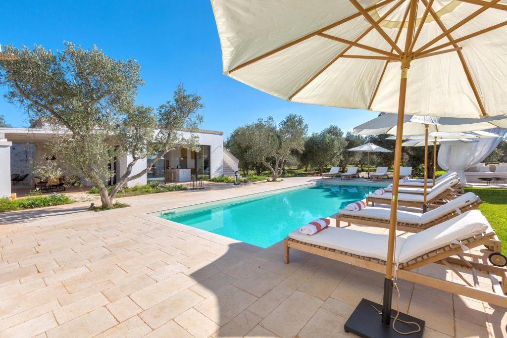 - une piscine avec 2 chaises longues et un parasol dans l'établissement Casa Diora by Perle di Puglia, à Carovigno