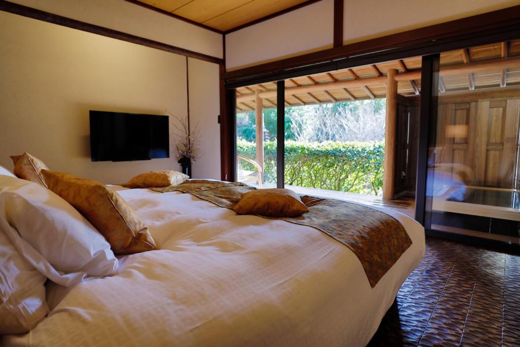 une chambre avec un grand lit blanc avec une grande fenêtre dans l'établissement Sakahijiri gyokushoen, à Izu