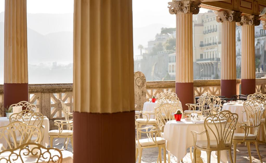 un restaurant avec des tables et des chaises blanches et un balcon dans l'établissement Bellevue Syrene, à Sorrente