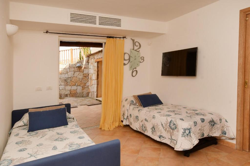 une chambre avec deux lits et une télévision au mur dans l'établissement [Villa indipendente piscina privata] e vista mare, à Cala Bitta 15 autres photos