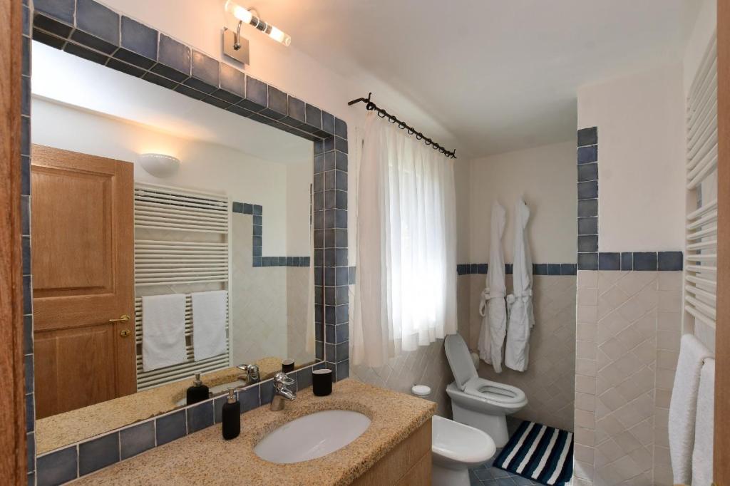 une salle de bain avec un lavabo, des toilettes et un miroir dans l'établissement [Villa indipendente piscina privata] e vista mare, à Cala Bitta