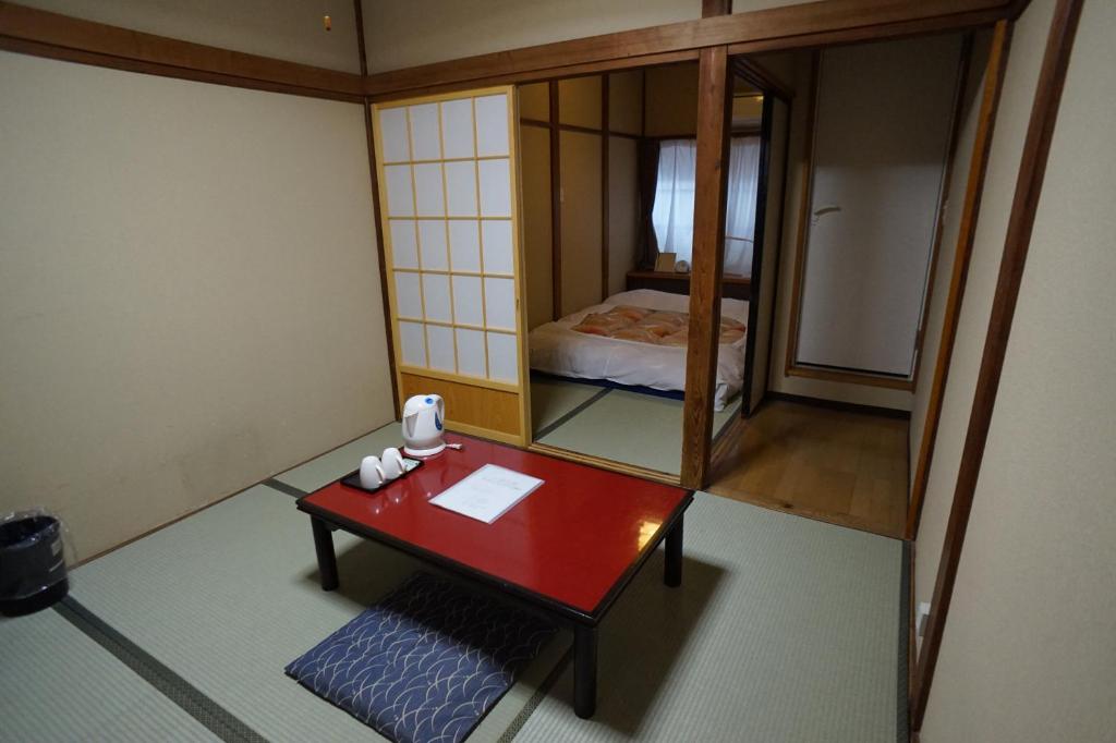 Cette petite chambre comprend une table rouge et un miroir. dans l'établissement Ryokan Katsutaro, à Tokyo