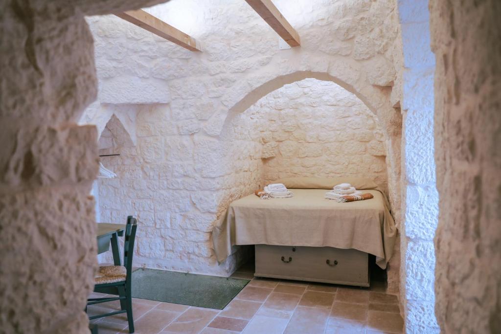 Cette chambre est dotée d'une table et d'un mur en pierre. dans l'établissement Trullo Mamas, à Ostuni