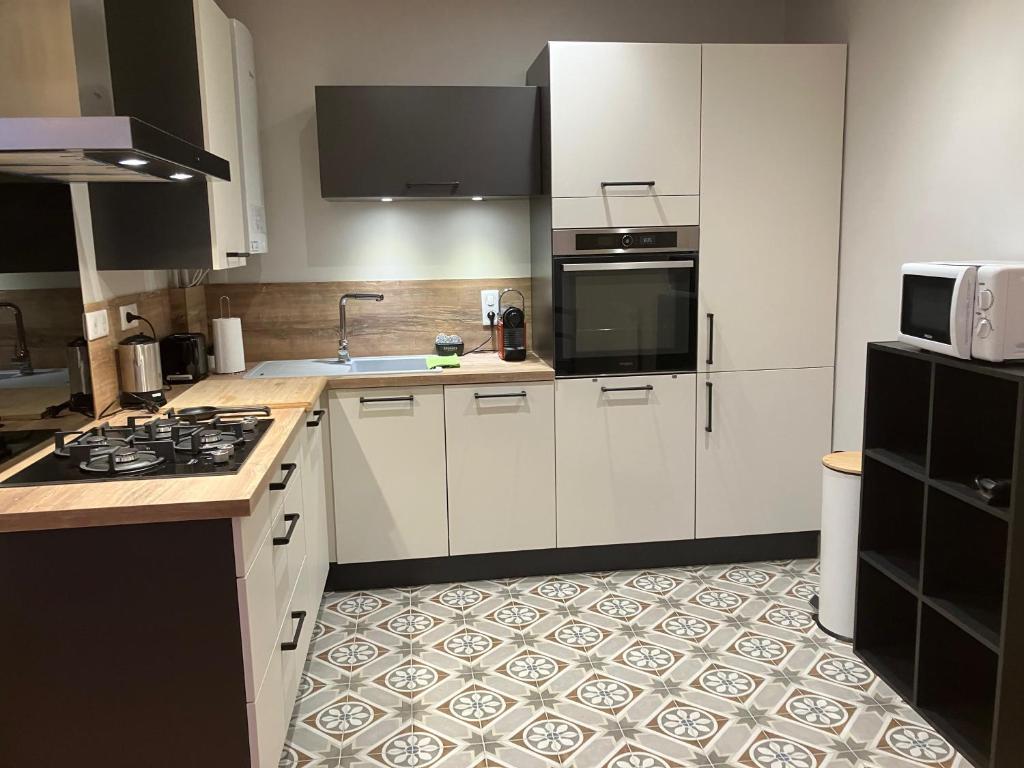 une cuisine avec des armoires blanches et un sol carrelé dans l'établissement Studio Quartier Château - Wifi - Garage individuel à clé - Electroménager complet, à Pau 4 autres photos