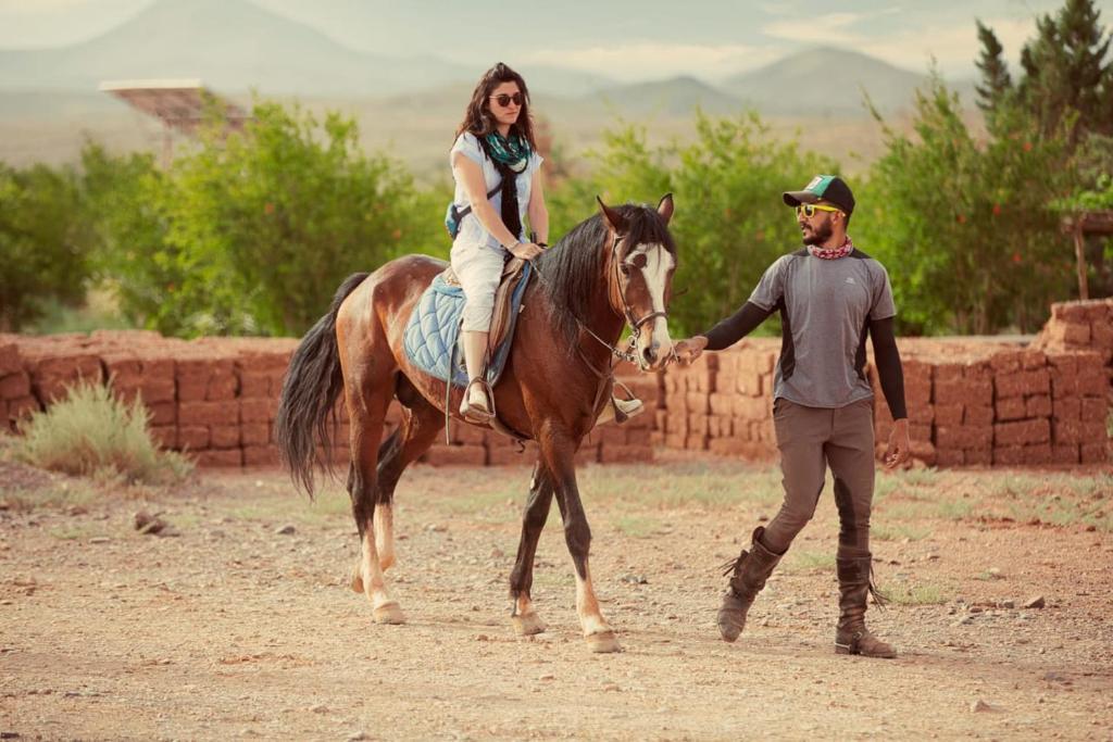 Un homme dirige une femme sur un cheval dans l'établissement Ecolodge l'île de Ouarzazate, à Ouarzazate