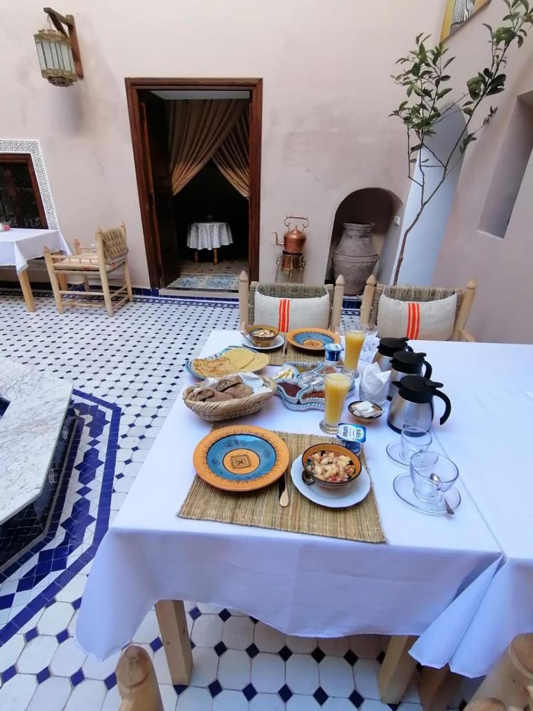 - une table blanche avec de la nourriture et des boissons dans l'établissement Dar Aouinti, à Marrakech