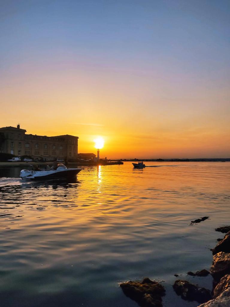 un coucher de soleil sur une étendue d'eau avec deux bateaux dans l'établissement Le Nid Marin,Un Voilier Pour Deux Sète Vieux Port, à Sète