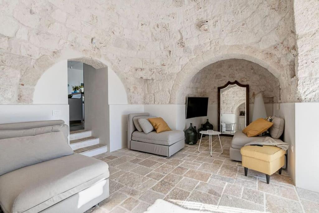 - un salon avec deux lits et un mur en pierre dans l'établissement Trullo Strangio by Raro Villas, à Ostuni