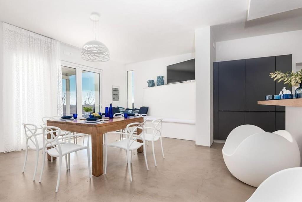 une salle à manger avec une table en bois et des chaises blanches dans l'établissement Trullo Strangio by Raro Villas, à Ostuni