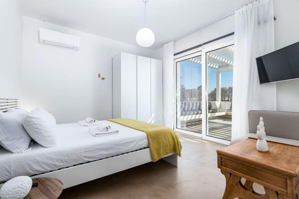 une chambre blanche avec un lit et un balcon dans l'établissement Trullo Strangio by Raro Villas, à Ostuni 31 autres photos