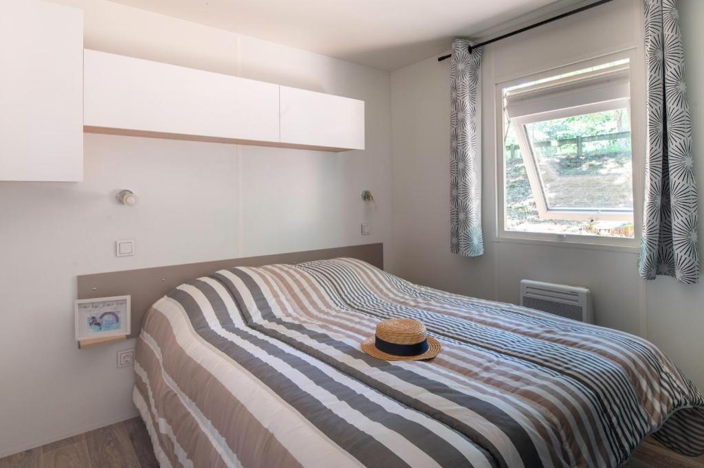 une chambre avec un lit avec un chapeau dessus dans l'établissement Camping maeva Escapades Les Lacs d'Armagnac, à Bretagne-dʼArmagnac