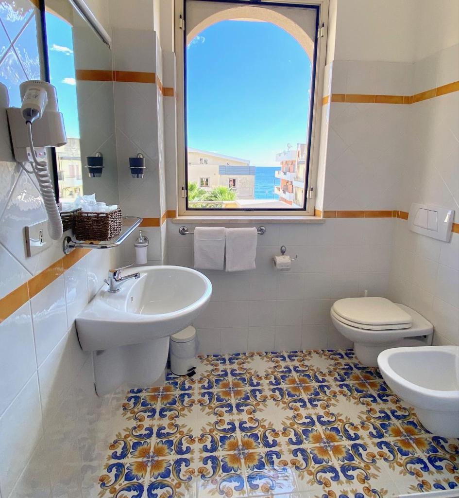une salle de bain avec un lavabo et des toilettes et une fenêtre dans l'établissement Hotel Sylesia, à Letojanni