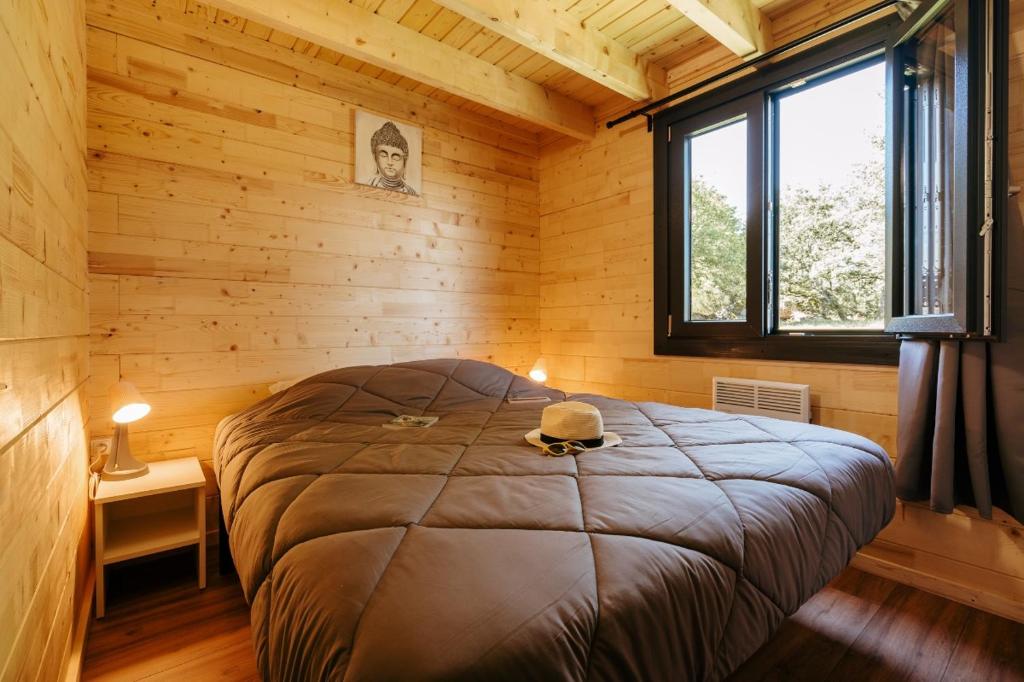 une chambre avec un lit dans une cabane en bois dans l'établissement maeva Respire Cottage de Brocéliande, à Caro