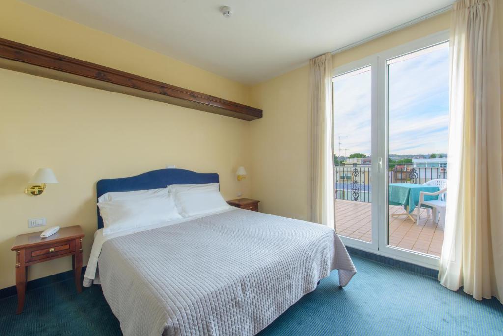 - une chambre avec un lit et une grande fenêtre avec un balcon dans l'établissement Palace Hotel Domus Mea Riccione, à Riccione