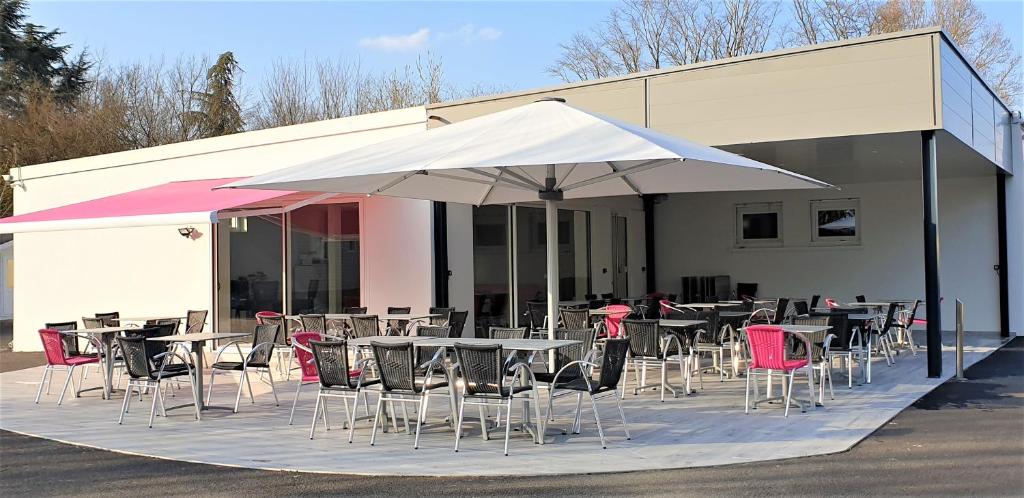 un groupe de tables et de chaises avec un parapluie dans l'établissement Camping de l'Ill, à Mulhouse