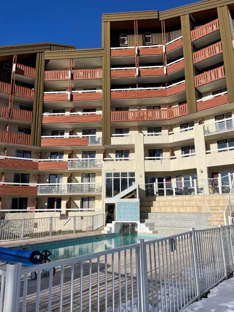 un immeuble d'appartements avec une piscine en face dans l'établissement Appart 4/5 pers résidence 4* des Bergers pieds des pistes, à L'Alpe-d'Huez