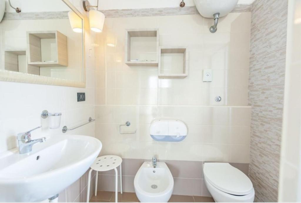 une salle de bain blanche avec un lavabo et des toilettes dans l'établissement Hotel La Torre, à Cervia
