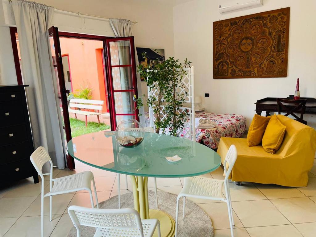 un salon avec une table en verre et un canapé jaune dans l'établissement Regina Del Mare Holiday Apartments, à Tirrenia